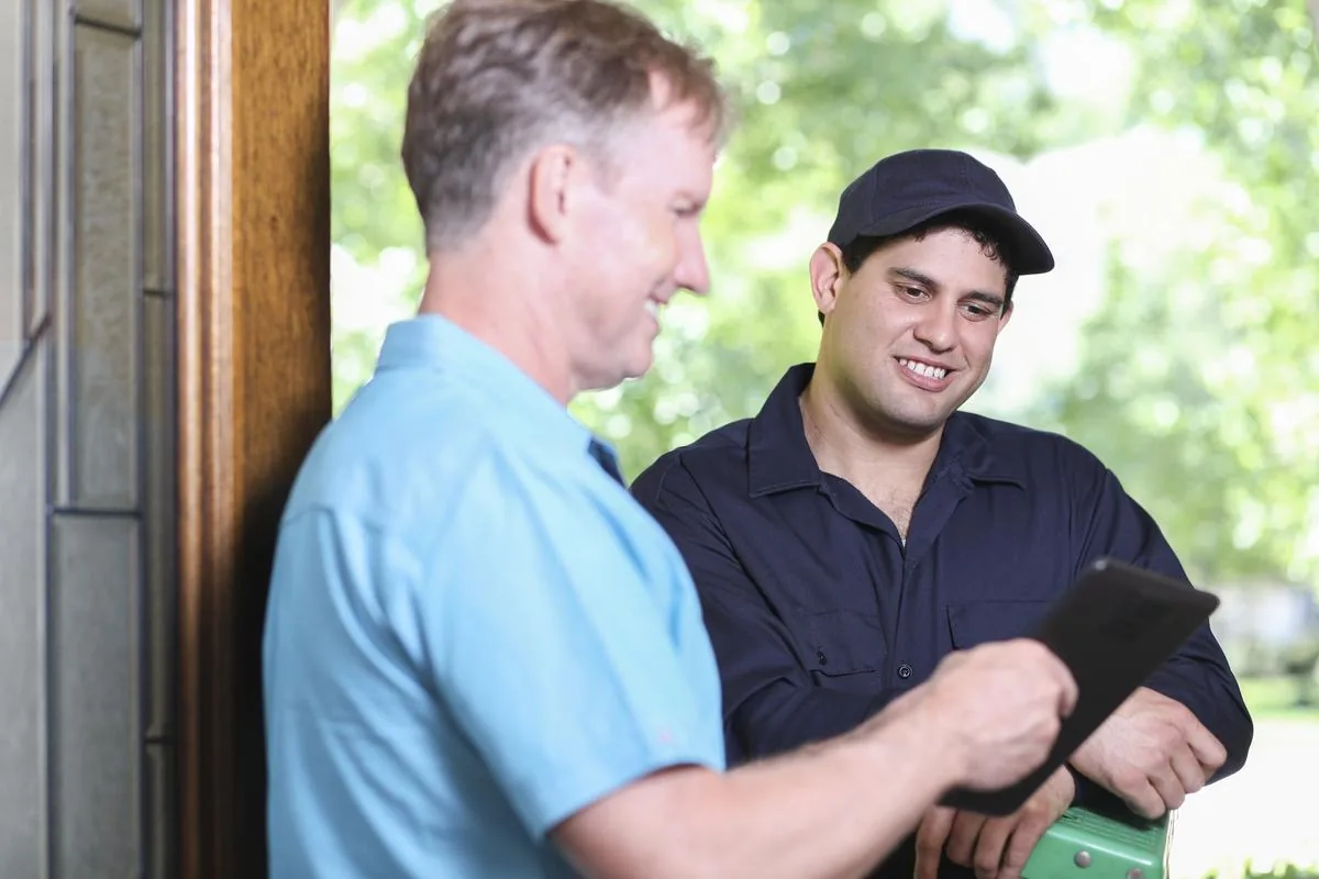Pest Troopers technician reviewing service details with homeowner at front door